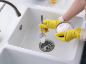 homeowner using baking sode - one of the many home remedies - to unclog sink drain