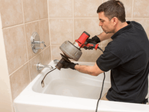 plumber clearing a drain line with auger